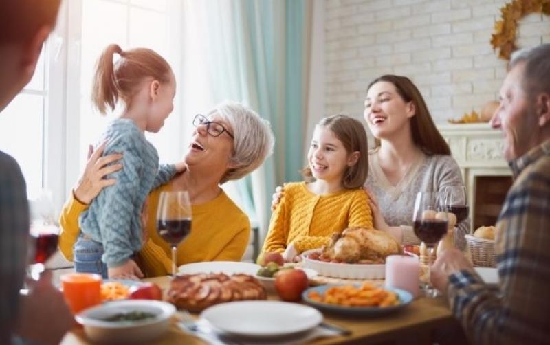 Family gathered and laughing at the dinner table for a holiday meal.